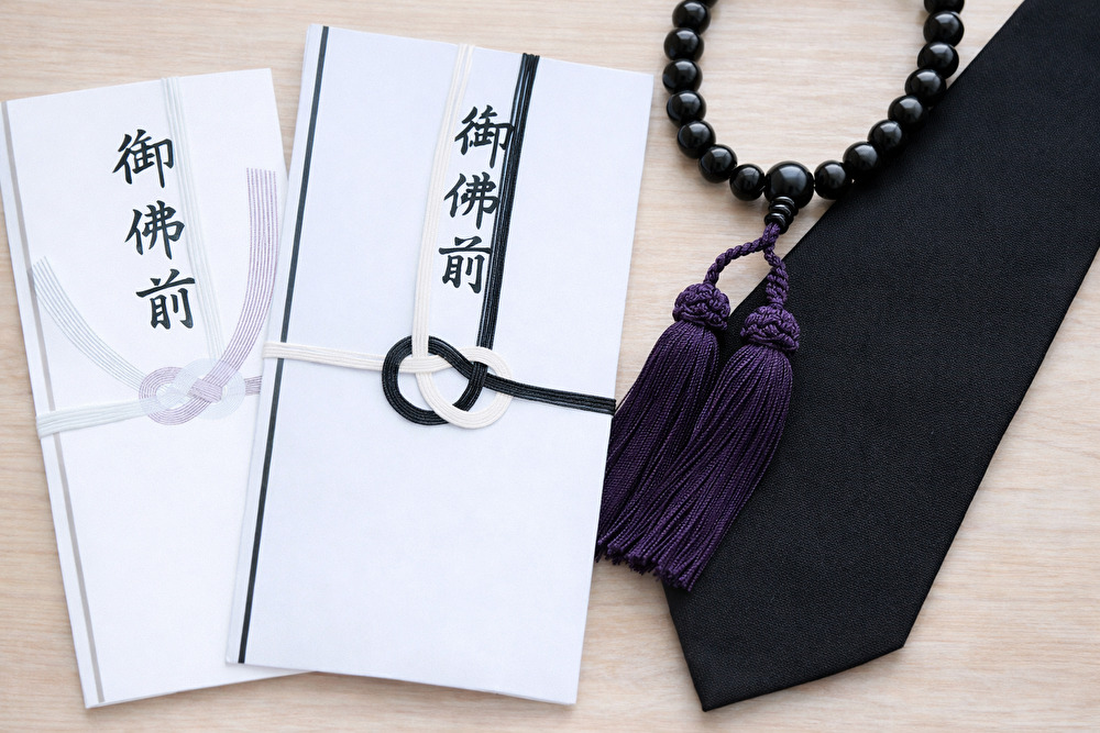 御仏前の香典袋と数珠、黒ネクタイを並べた法要・法事のイメージ