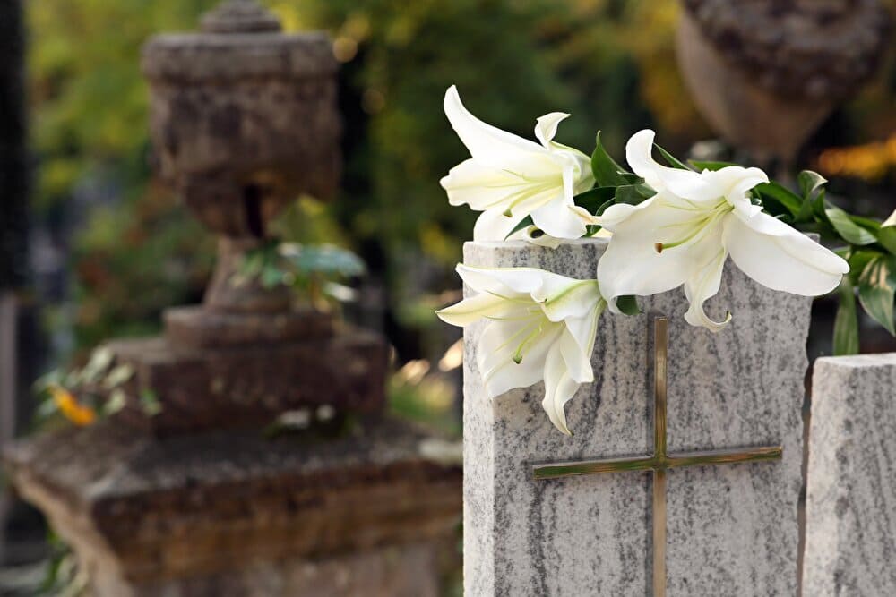 White lilies on granite tombstone outdoors, space for text. Funeral ceremony.　出典：123rf